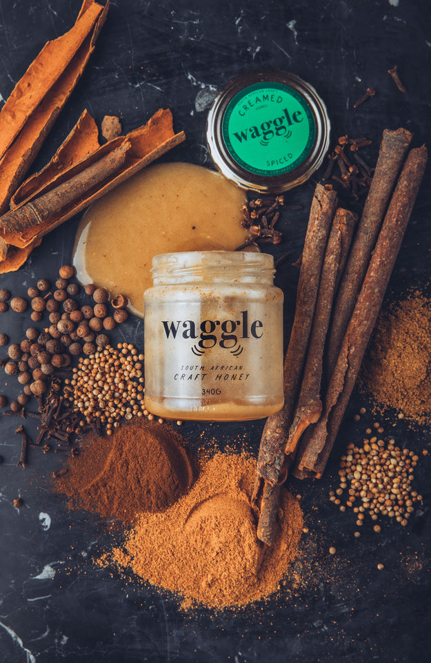 Waggle's Raw Spiced Creamed Craft Honey displayed with a scattering of spices