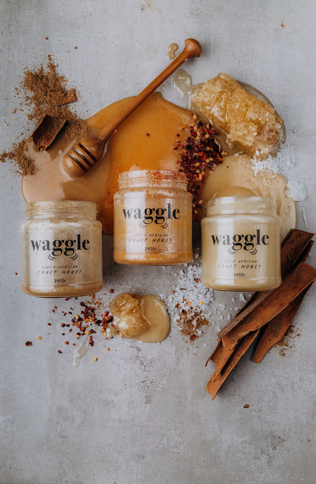 Waggle's Queen Bee Trio set, a combo of Salted, Spiced and Chilli honey, visually displayed surrounded by spices