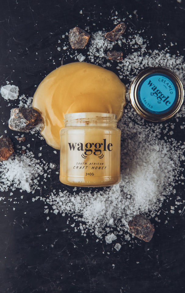 Waggle Salted Craft Honey artistically displayed surrounded by a scattering of salt products